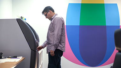 Joe Dougherty, Gerente do departamento de design para a ARC North America, verifica uma execução de impressão 3D na ProJet 260Plus. A impressora 3D é ecológica e segura para uso em um ambiente de escritório.