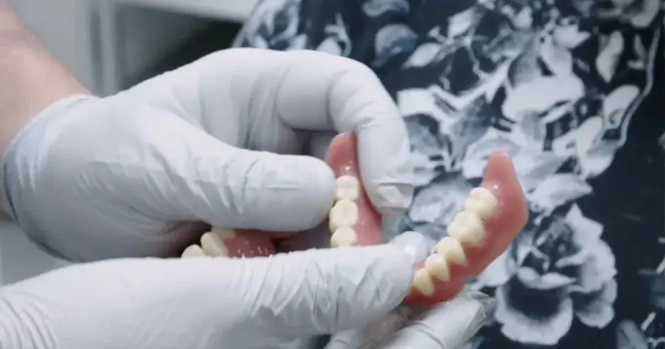 Um dentista dando novas próteses a um cliente