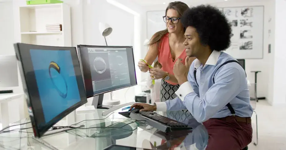 2 pessoas projetando um relógio e editando o arquivo em um monitor grande