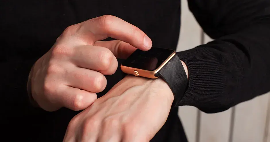 um homem usando um relógio e apontando para as características do relógio